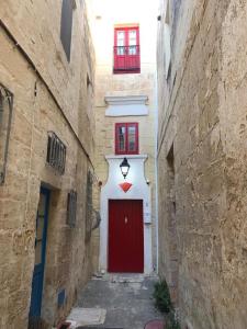 czerwone drzwi na białym budynku z czerwonymi oknami w obiekcie The Hidden Gem Boutique Hotel w mieście Rabat