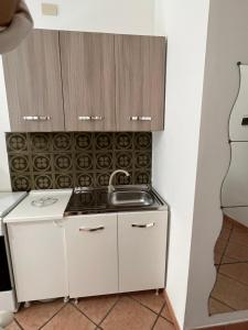 a small kitchen with white cabinets and a stove at Artista studio in Cefalù