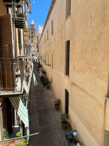 an alley between two buildings with potted plants at Artista studio in Cefalù