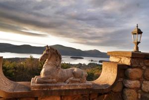 a statue of a horse sitting on a stone wall at HIGHLANDS CASTLE overlooking Lake George plus 2 other CASTLES & SUITES in Bolton Landing