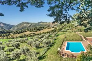 an estate with a swimming pool in a field with mountains at Villamena in Assisi