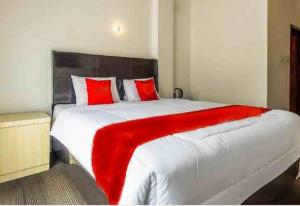 1 dormitorio con 1 cama blanca grande con almohadas rojas en THE TISPA SYARIAH RESIDENCE, en Palembang