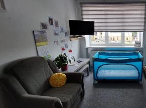a living room with a couch and a crib at Dzīvoklis 17 in Rūjiena