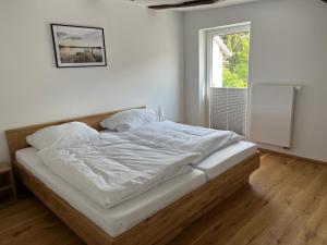 a bedroom with a bed with white sheets and a window at Ferienwohnung Ederblick in Wabern