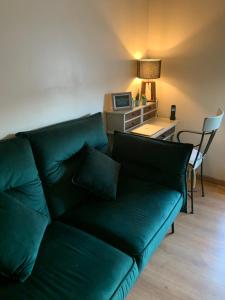 One Bedroom Appartement - Paris في باريس: غرفة معيشة مع أريكة خضراء ومكتب