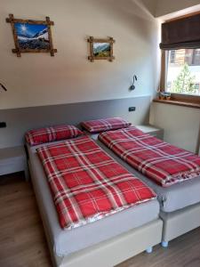 two beds in a small room with red and white blankets at Appartamenti Elena & Milva in Livigno