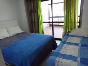 a bedroom with two beds and a window with green curtains at Apto na cobertura a 190 m do mar no Rio de Janeiro in Rio de Janeiro