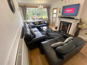 Detached Bungalow II Big Garden II Pet Friendly في Hednesford: غرفة معيشة مع كنب جلدي ومدفأة