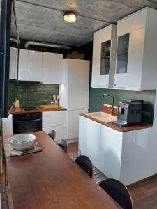 a kitchen with white cabinets and a wooden table at Loksapark1 in Loksa
