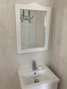 a white bathroom with a sink and a mirror at The Secret Garden in Killala