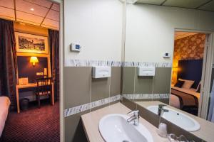 Un baño con lavabo y espejo y un dormitorio. en Hôtel Des Trois Gares, en París