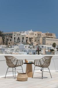 Duas cadeiras e uma mesa numa varanda com uma cidade em CASA DE SAL em Naxos Chora