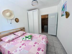 sypialnia z łóżkiem z różową narzutą w obiekcie Gites Les 7 C w mieście Le Gosier