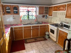 uma cozinha com armários de madeira e um forno com placa de fogão em Homely environment ideal for a home away from home em Gros Islet