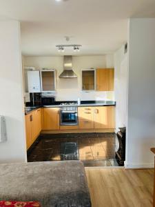 愛丁堡的住宿－FABULOUS 2BED 2BATH Ground Floor SERVICED ACCOMMODATION Near CITY，厨房配有木制橱柜和炉灶烤箱。