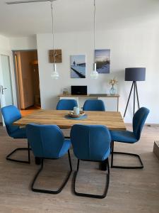 uma sala de jantar com uma mesa de madeira e cadeiras azuis em Meehrblick App 215 em Zingst