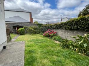 um quintal com uma parede de tijolos e flores cor-de-rosa em Sandymount House & Garden em Dublin
