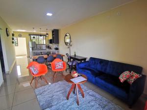 a living room with a blue couch and orange chairs at Loky's Apartments La Fortuna in Fortuna