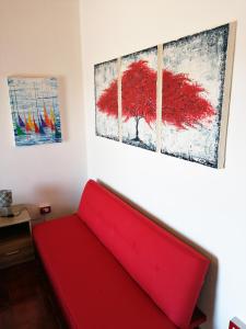 a red couch in a room with paintings on the wall at Casa Alessandria in Alessandria