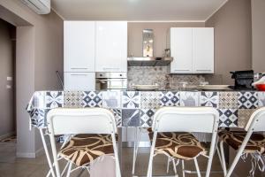 una cocina con armarios blancos y una barra con taburetes en Etna Sunshine Piedimonte, en Piedimonte Etneo