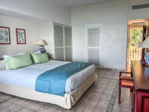 a bedroom with a large bed and a desk at Auberge de la Vieille Tour in Le Gosier