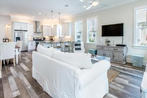 a living room with white furniture and a kitchen at Grayt Paradise in Grayton Beach