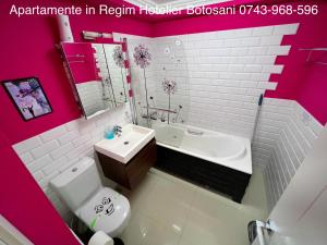Baño de color rosa con lavabo, bañera y aseo en Apartament nemaipomenit de frumos Super accesibil, en Botoşani
