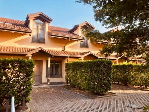 a large yellow house with a brick driveway at Hotel Malpensa INN Aereoporto in Tornavento