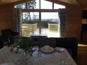 a dining room with a table and a large window at Birch Lodge, Pitlandie - Luxury 2 Bedroom Lodge with Sauna in Perth