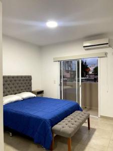 Un dormitorio con una cama azul y un banco en Hermoso departamento,totalmente amoblado c/cochera en Salta