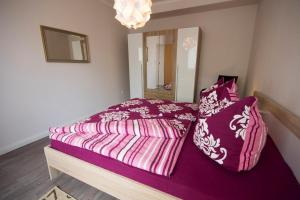 Schlafzimmer mit einem Bett mit lila Bettwäsche und Kissen in der Unterkunft Haus Frauenpreiss Whg. 52 in Cuxhaven