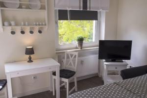 Schlafzimmer mit einem Schreibtisch, einem TV und einem Fenster in der Unterkunft Haus Frauenpreiss Whg. 61 in Cuxhaven