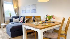 ein Wohnzimmer mit einem Tisch und einem blauen Sofa in der Unterkunft Strandhaus Nordseebrandung Fewo A4.2 in Cuxhaven