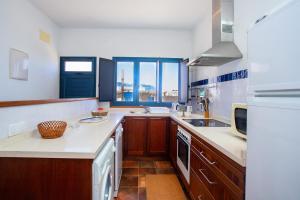 a kitchen with wooden cabinets and white counter tops at Eslanzarote El Ancla House, wifi, Sea views in Caleta de Sebo