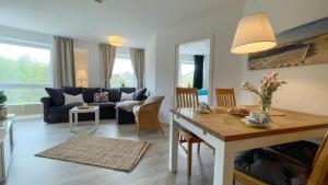 ein Wohnzimmer mit einem Tisch und einem Sofa in der Unterkunft Strandhaus Nordseebrandung Fewo A3.3 in Cuxhaven