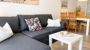 ein Wohnzimmer mit einem blauen Sofa und einem Tisch in der Unterkunft Strandhaus Nordseebrandung Fewo D1.1 in Cuxhaven