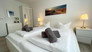 2 weiße Betten mit Kissen auf einem Zimmer in der Unterkunft Strandhaus Nordseebrandung Fewo C1.1 in Cuxhaven