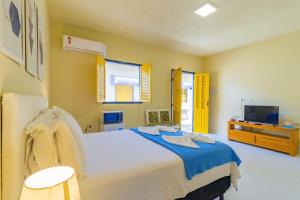 1 dormitorio con 1 cama grande y TV en Suítes B6, en Porto de Galinhas