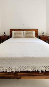 un grande letto con lenzuola e cuscini bianchi di Laina Traditional Guest House ad Apérathos