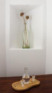 un jarrón de cristal sentado en una bandeja de madera con dos vasos en Laina Traditional Guest House, en Apérathos