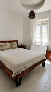 Laina Traditional Guest House في Apérathos: غرفة نوم بيضاء مع سرير خشبي في غرفة