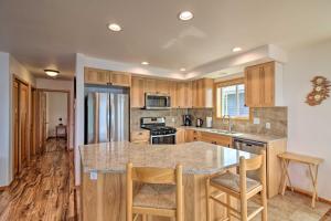 a kitchen with wooden cabinets and a island with bar stools at Oceanfront Craig Apt Grill, Fishing On-Site! in Craig