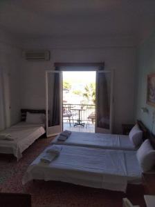 two beds in a bedroom with a view of the ocean at Ammoudia Rooms in Agia Marina Aegina