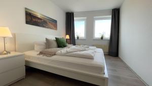 una camera da letto con un grande letto bianco con due finestre di Strandhaus-Nordseebrandung-Fewo-D1-4 a Cuxhaven