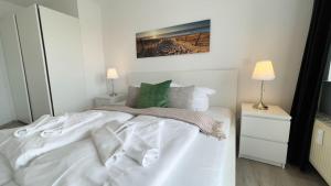 Strandhaus-Nordseebrandung-Fewo-D1-5 في كوكسهافن: سرير أبيض في غرفة نوم بها مصباحين