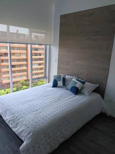 ein Schlafzimmer mit einem großen weißen Bett mit blauen Kissen in der Unterkunft Loft Moderno en Bogotá -Usaquén in Bogotá