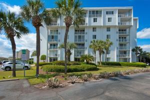 a white apartment building with palm trees and a car at Dolphin Point #406C in Destin