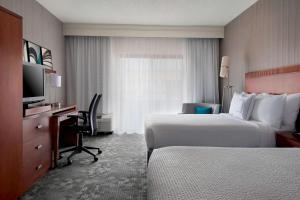 a hotel room with two beds and a desk and a television at Sonesta Select Whippany Hanover in Whippany