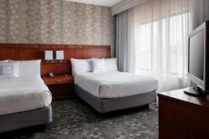 a hotel room with two beds and a flat screen tv at Sonesta Select Whippany Hanover in Whippany
