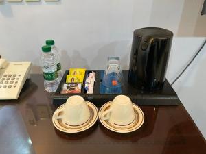 una mesa con dos tazas y platos y una cafetera en Arrawiya Alzahabia Hotel en Dammam